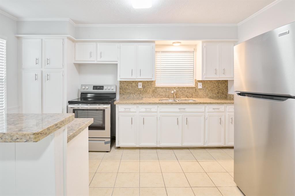 a kitchen with granite countertop a sink stove and refrigerator