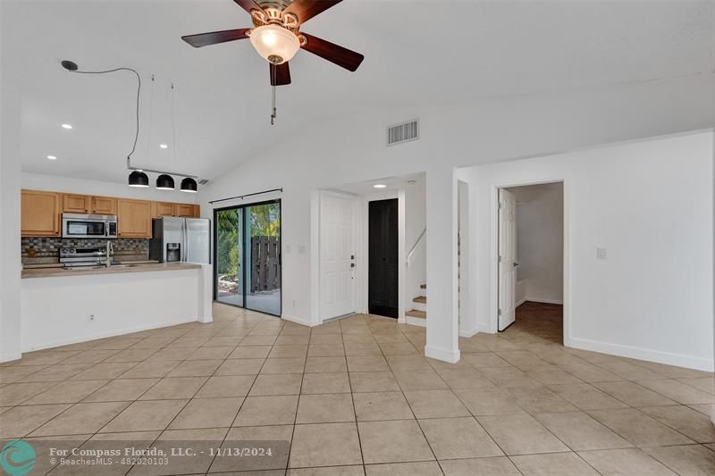 a view of an empty room with kitchen and a window