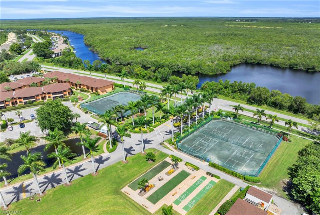 Birds eye view of community amenities showing pickleball, bocce ball, shuffleboard, and tennis courts along with a water view