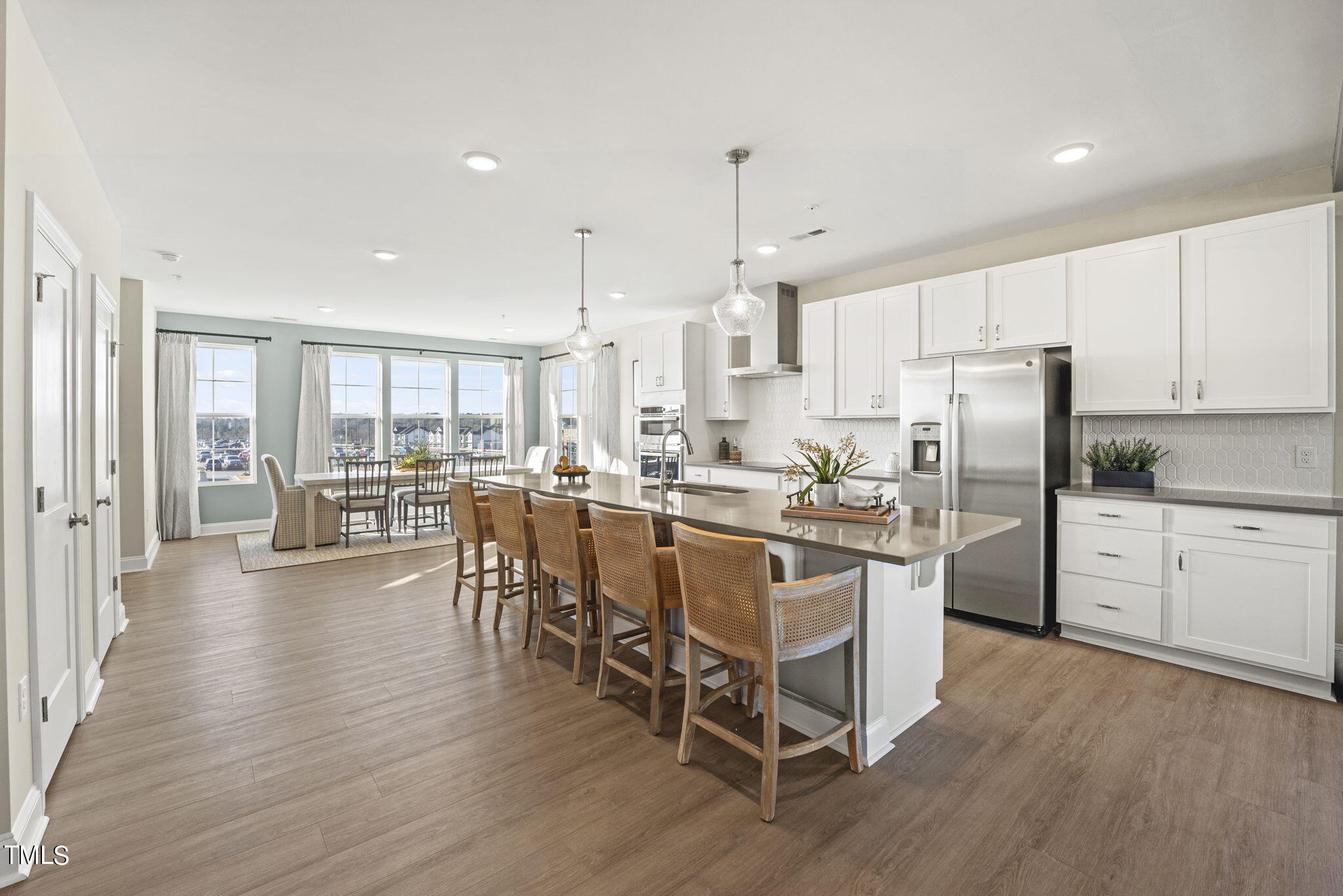 a kitchen with stainless steel appliances kitchen island granite countertop a table chairs stove and white cabinets