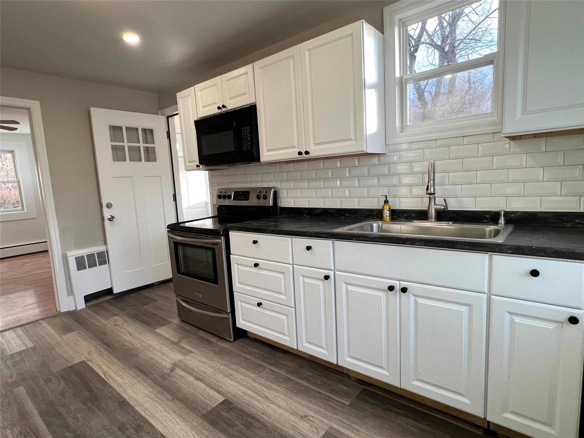 a kitchen with granite countertop white cabinets and stainless steel appliances