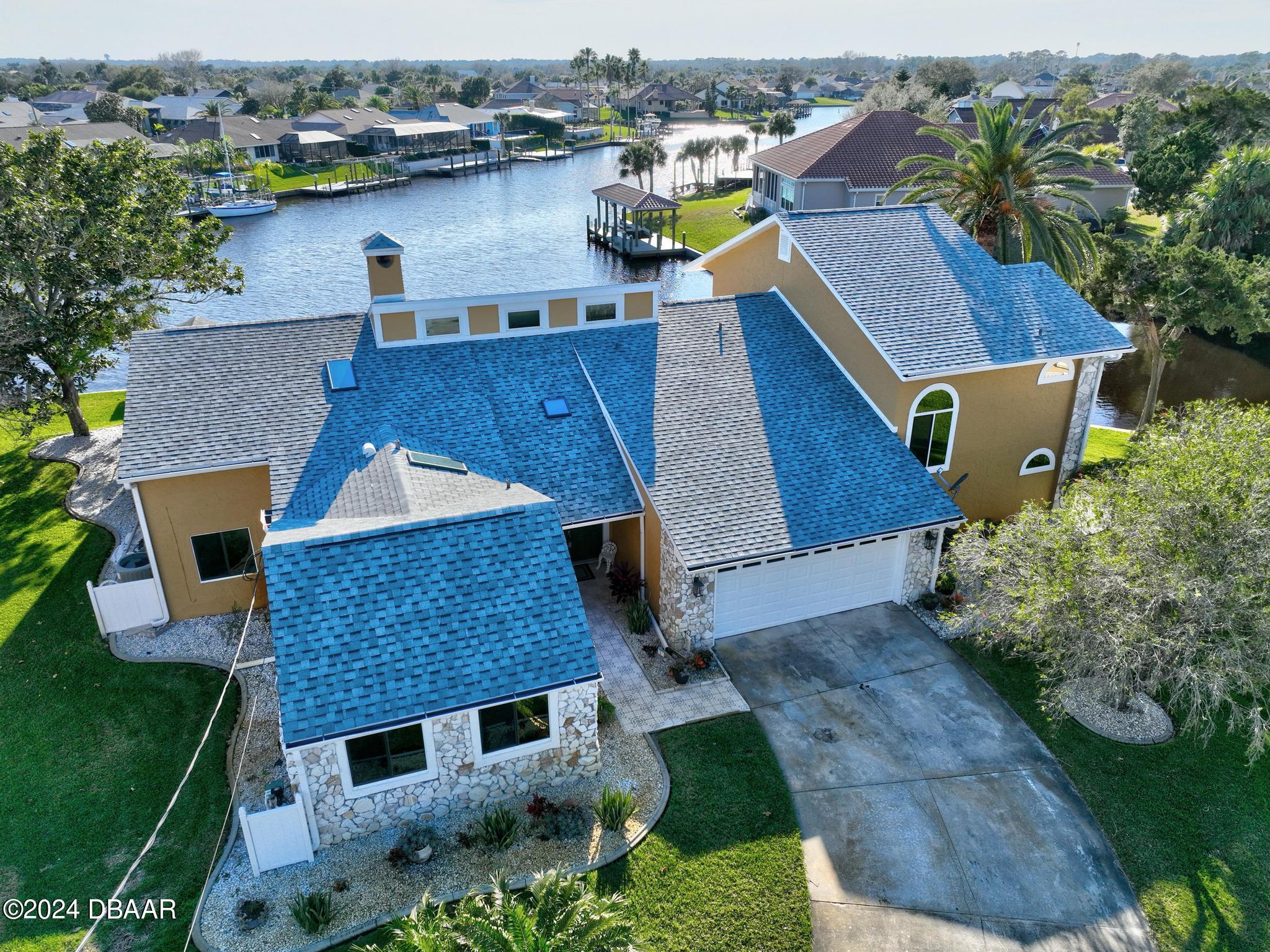 an aerial view of a house with a yard garage and lake view in back