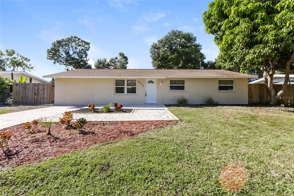 a front view of house with yard and trees in the background