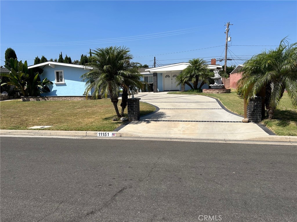 a view of a house with a yard and palm trees