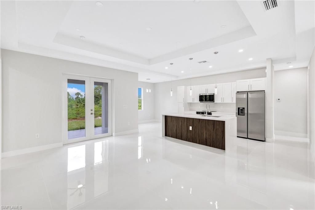 a large white kitchen with a sink stainless steel appliances and cabinets