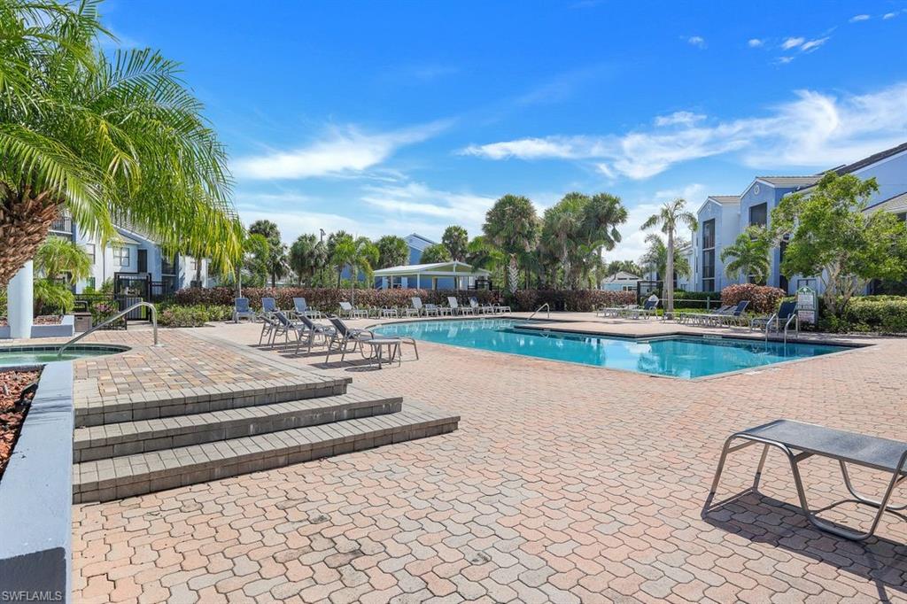 a view of a swimming pool with lawn chairs and plants