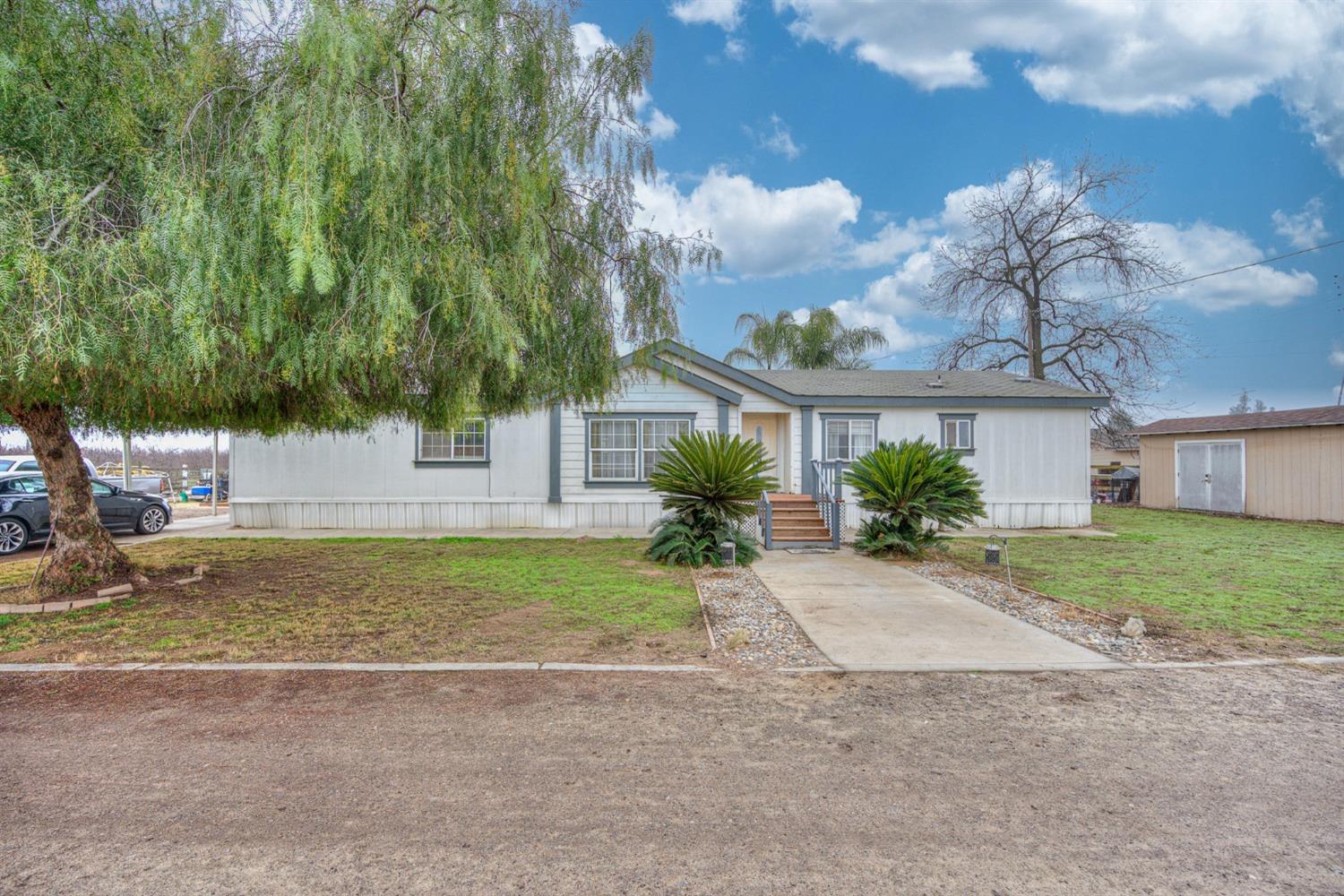 a view of a house with a yard and large tree