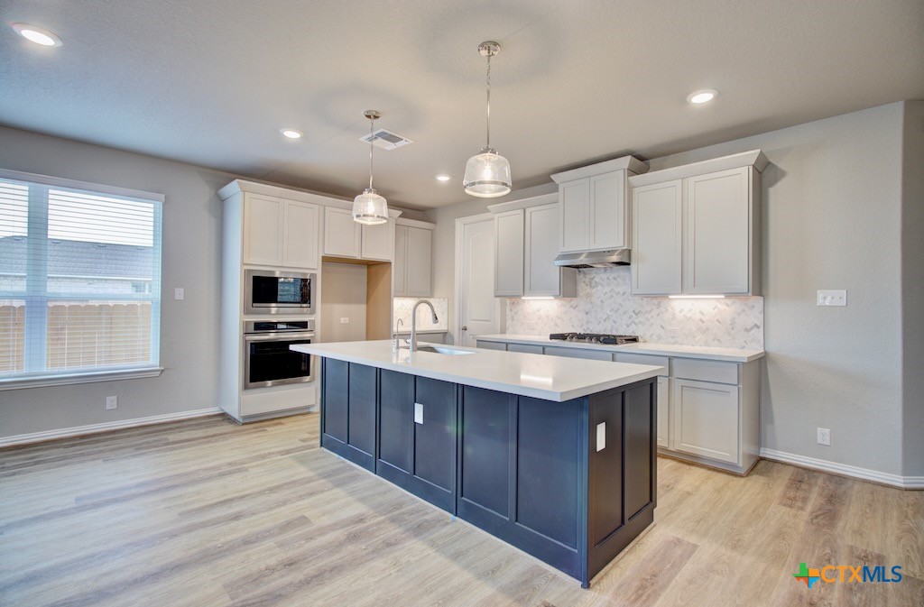 a kitchen with kitchen island a sink stainless steel appliances and cabinets