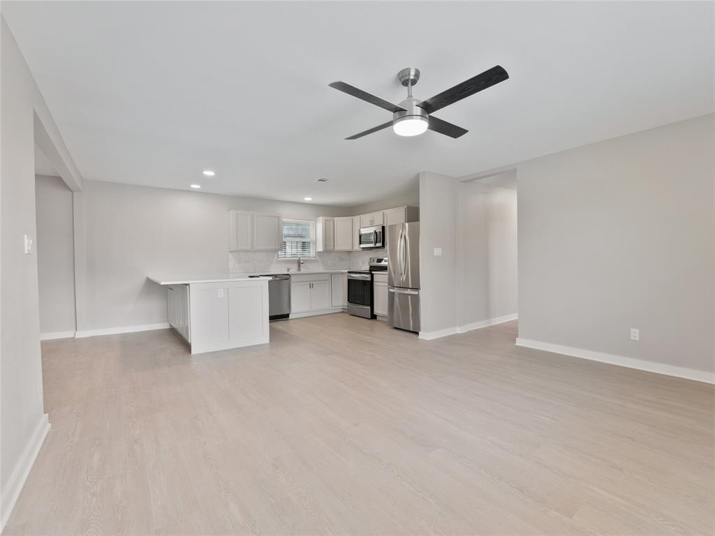 a view of a kitchen with a refrigerator a ceiling fan and stainless steel appliances