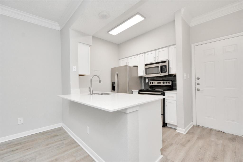 a kitchen with stainless steel appliances a sink a stove a microwave and cabinets