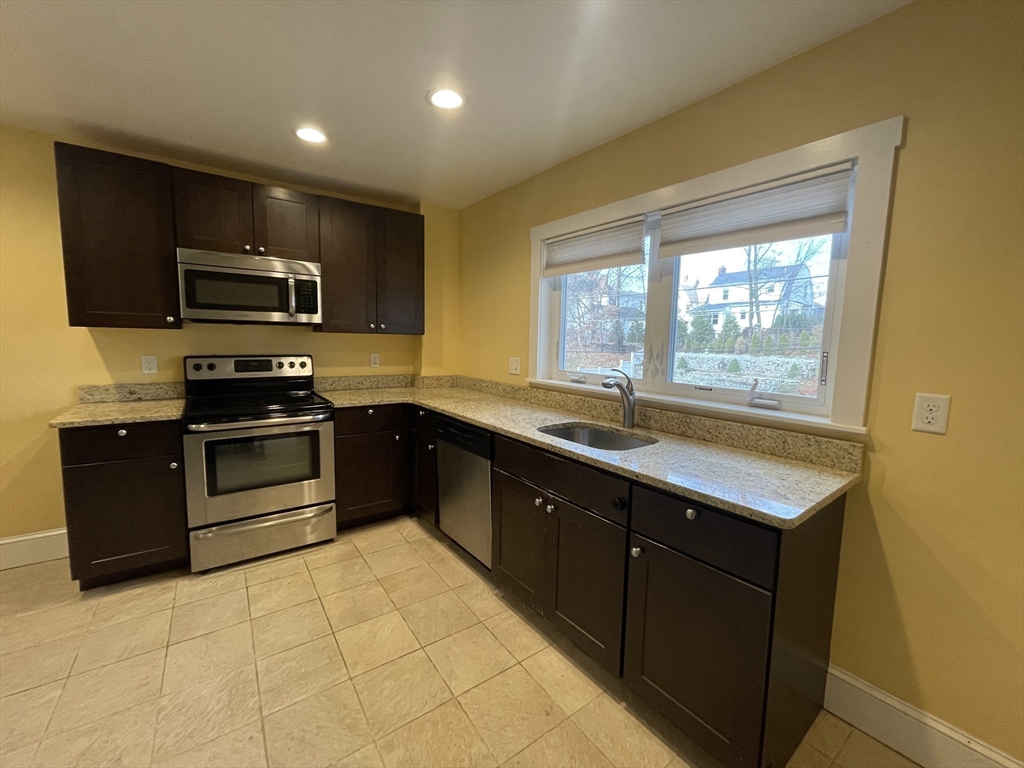 a kitchen with kitchen island granite countertop a stove sink and microwave