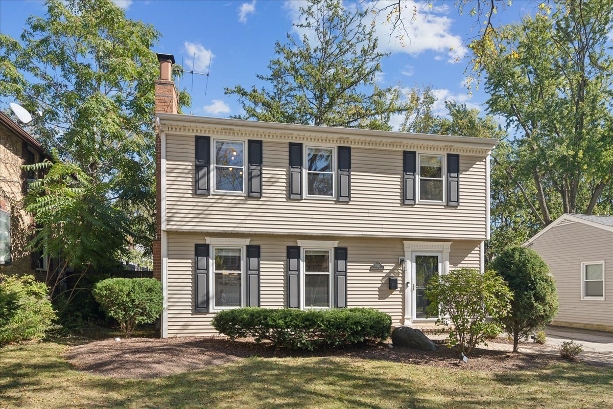 a front view of a house with yard and trees in the background