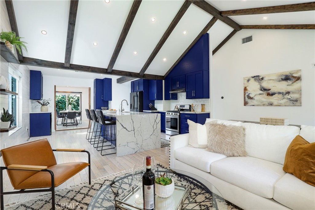 a living room with furniture kitchen view and a chandelier