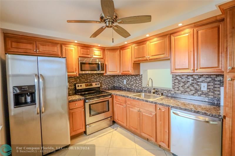 a kitchen with stainless steel appliances granite countertop a refrigerator and a sink