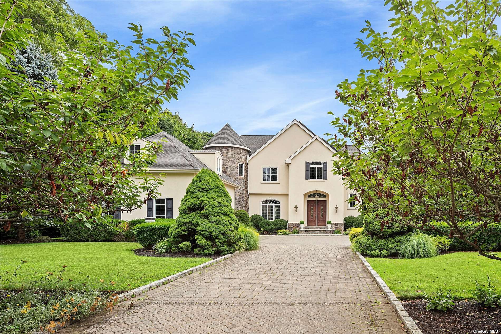 a view of a white house with a small yard and large tree