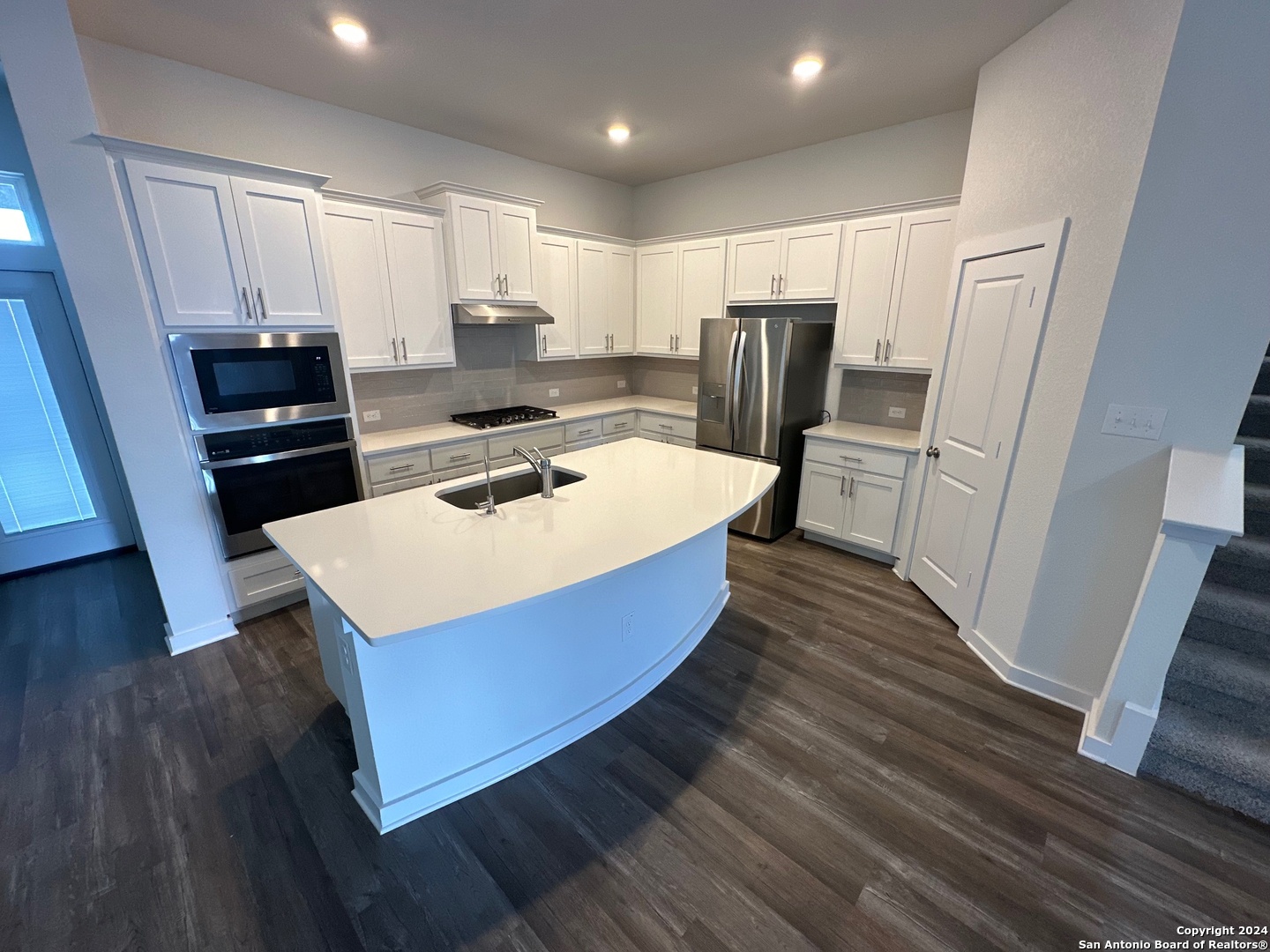 a kitchen with wooden floors a sink a stove a refrigerator and cabinets