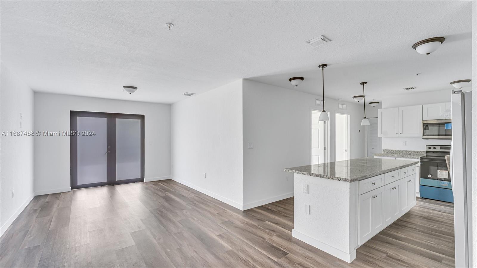 a large white kitchen with wooden floor