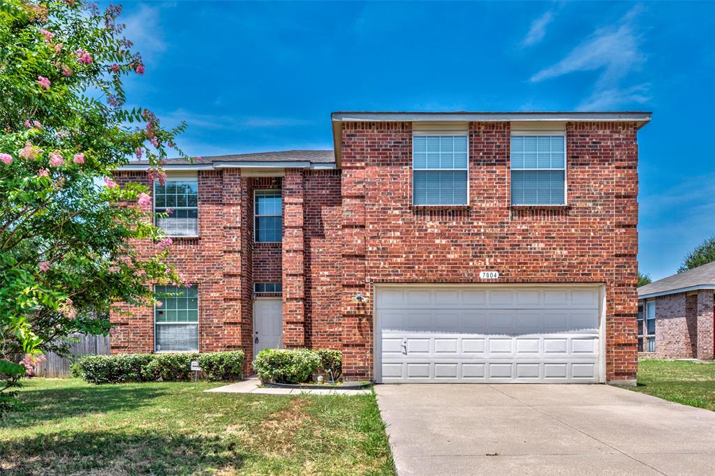 front view of a brick house with a yard