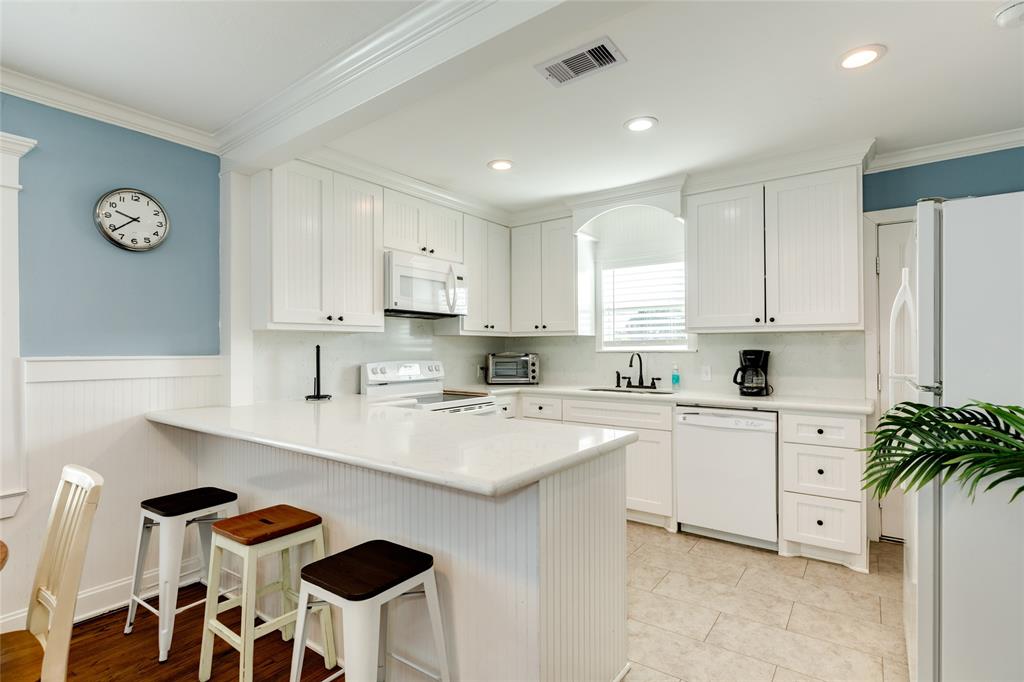 a kitchen with stainless steel appliances granite countertop a sink a stove a refrigerator and white cabinets