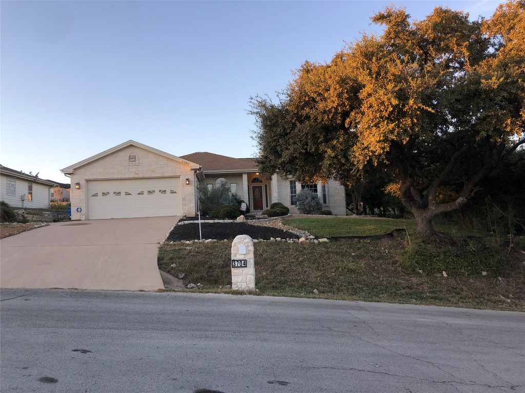 a front view of a house with a garden and tree