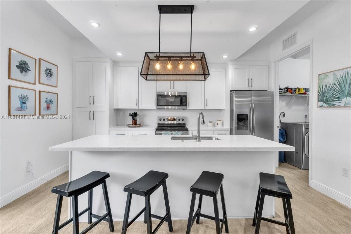 a kitchen with stainless steel appliances a dining table chairs and refrigerator