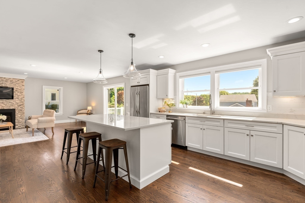 a large kitchen with cabinets chairs and wooden floor