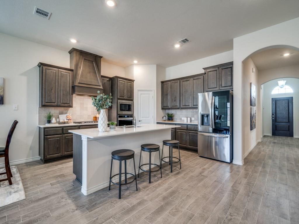 a kitchen with stainless steel appliances granite countertop a refrigerator a stove top oven a sink dishwasher and white cabinets with wooden floor