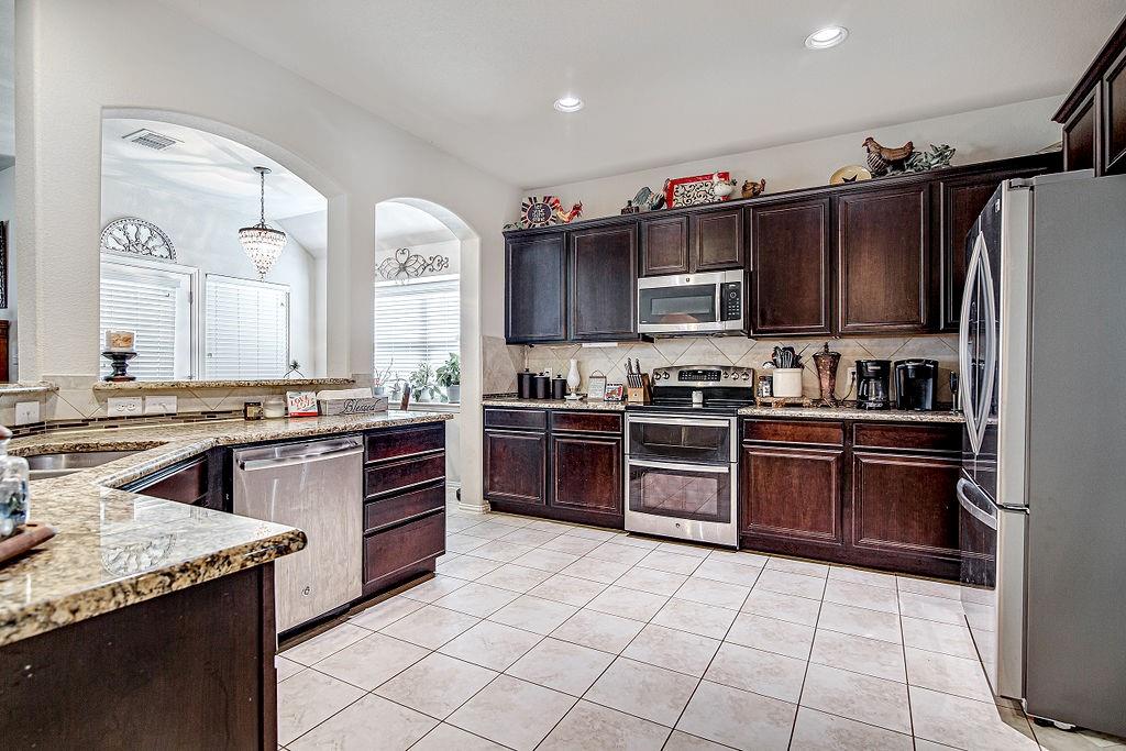 a kitchen with granite countertop a stove top oven sink and cabinets