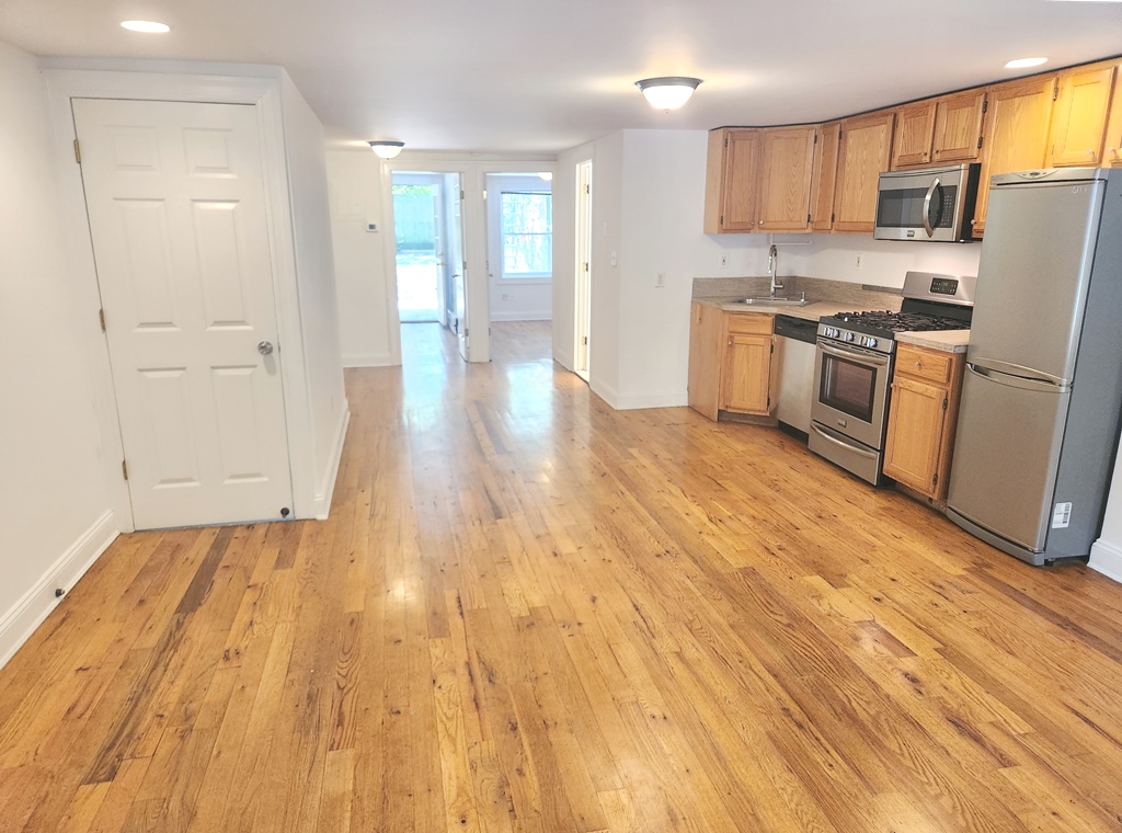 a view of kitchen with stainless steel appliances granite countertop a stove a sink dishwasher and a refrigerator with wooden floor