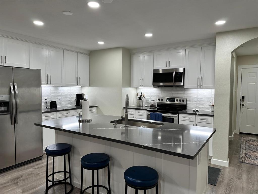 a kitchen with kitchen island granite countertop a sink counter top space cabinets and stainless steel appliances