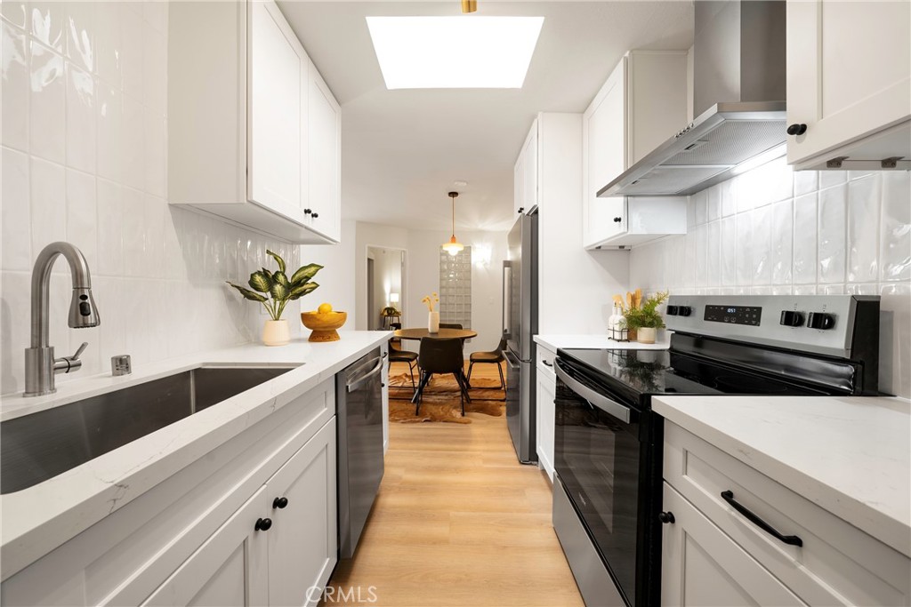 a kitchen with stainless steel appliances a sink a stove and cabinets