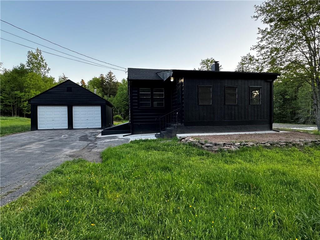 View of front of property with a garage, a front yard, and an outdoor structure