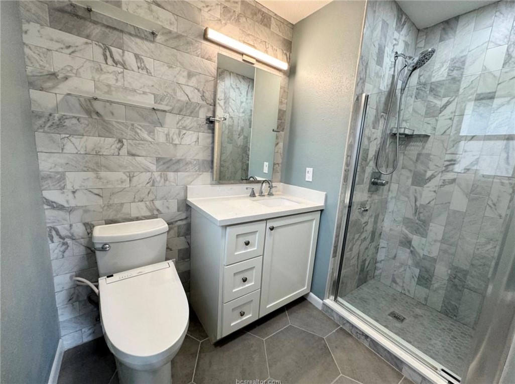 Bathroom with tile patterned floors, toilet, tiled