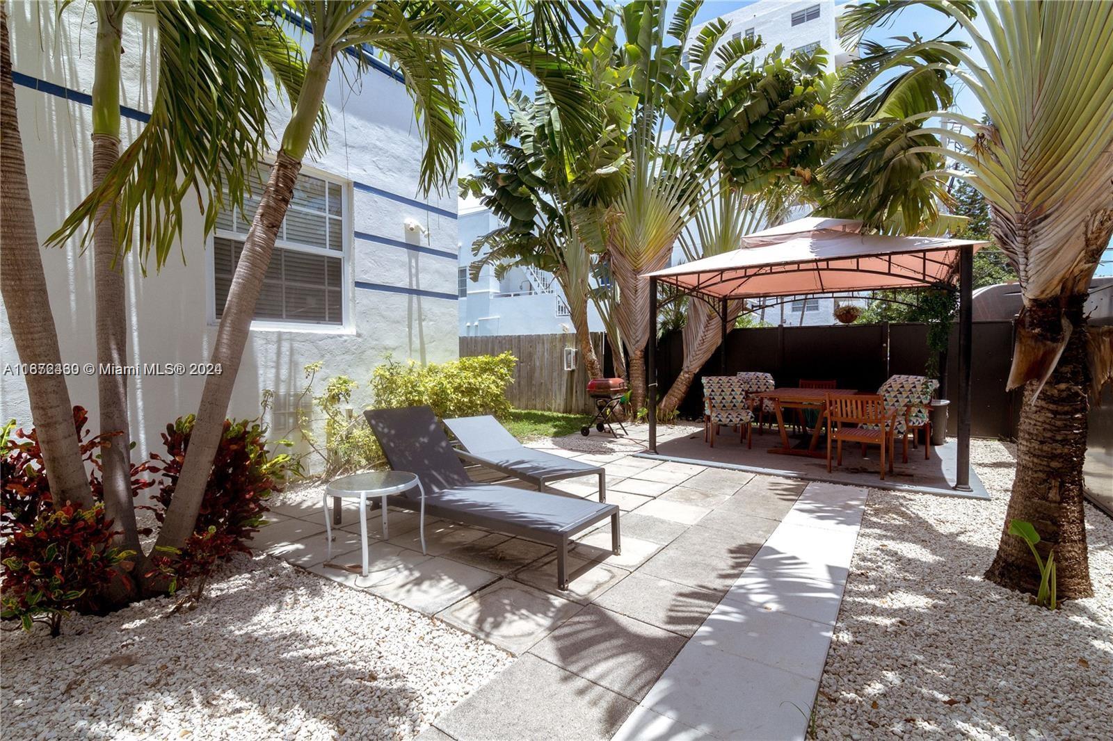 a view of a patio with table and chairs potted plants and a large tree