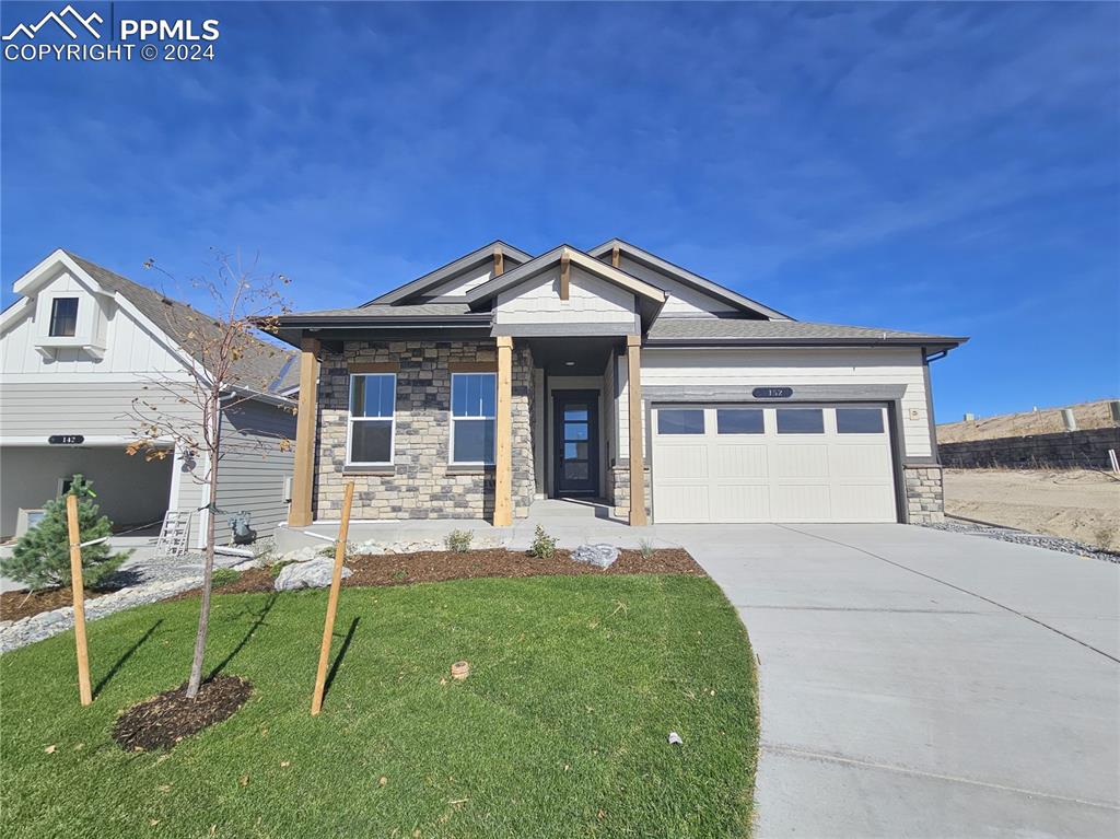 Craftsman inspired home with a garage and a front lawn