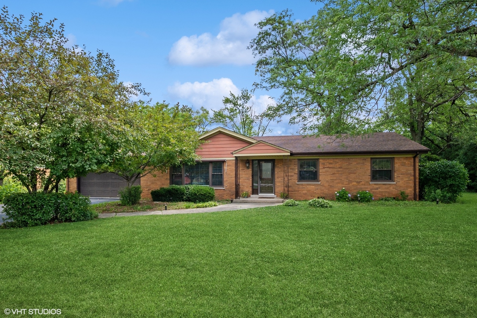 a front view of a house with a garden and trees