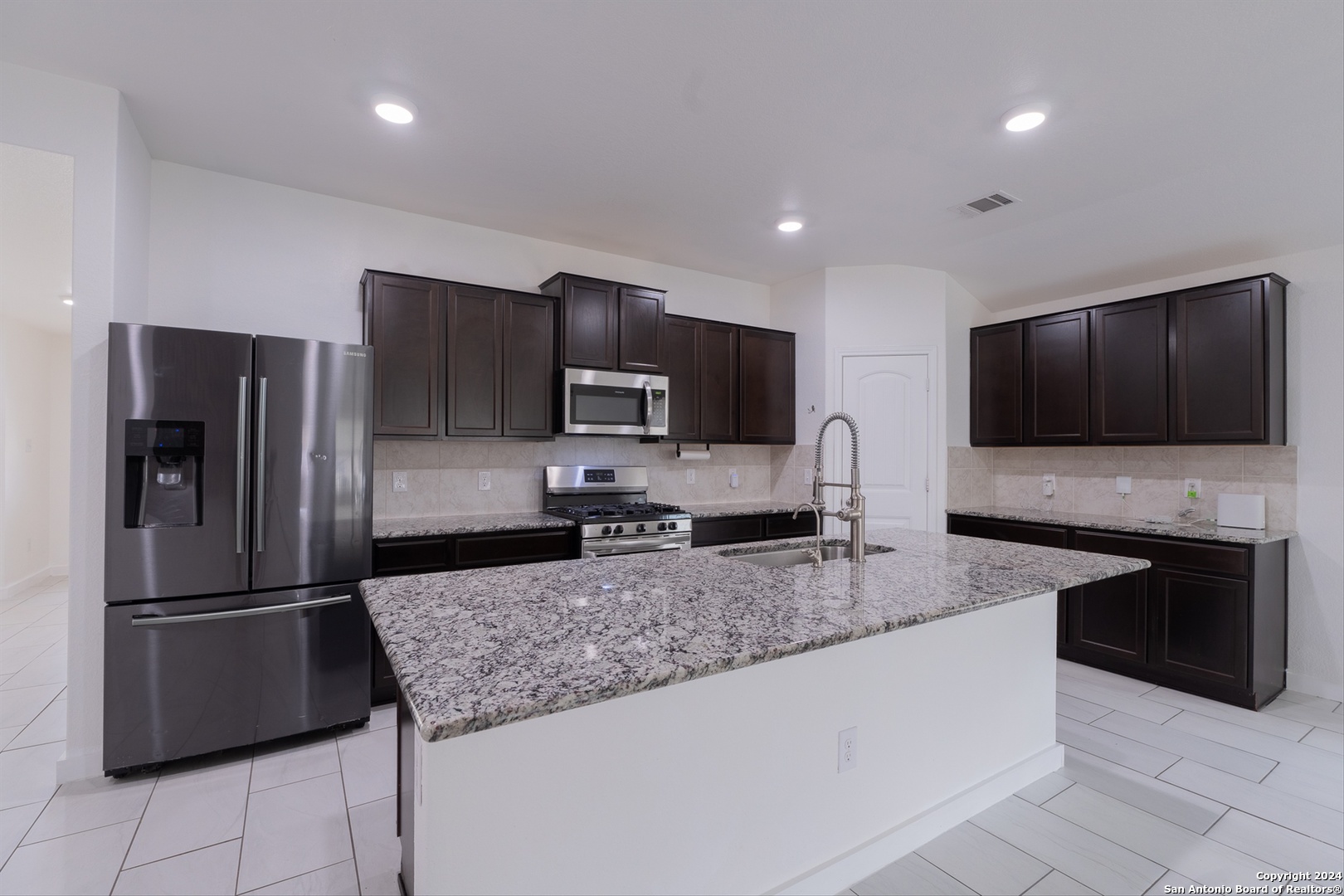 a kitchen with granite countertop a refrigerator and a sink