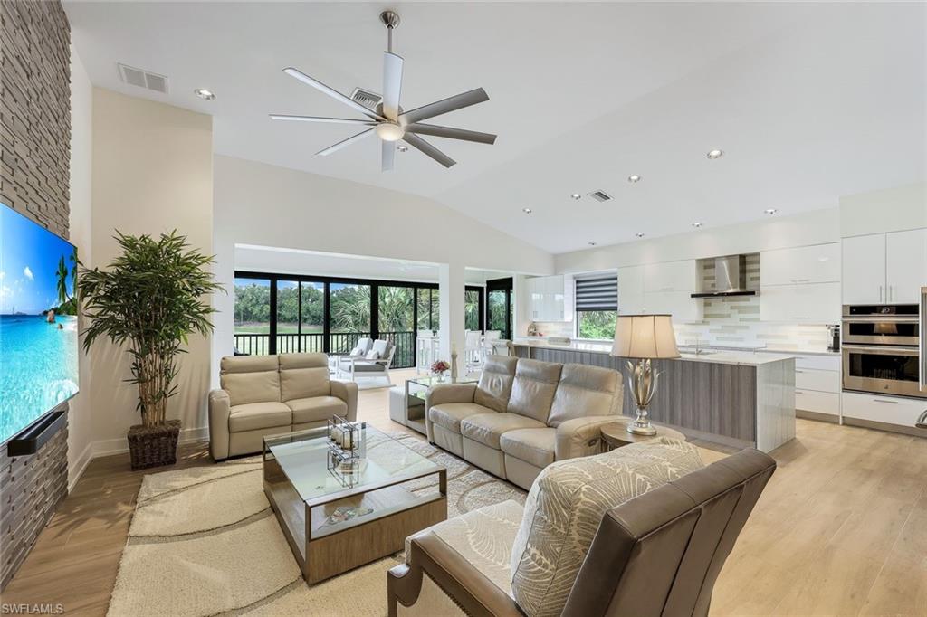 Living room with vaulted ceiling, ceiling fan, and light hardwood / wood-style floors