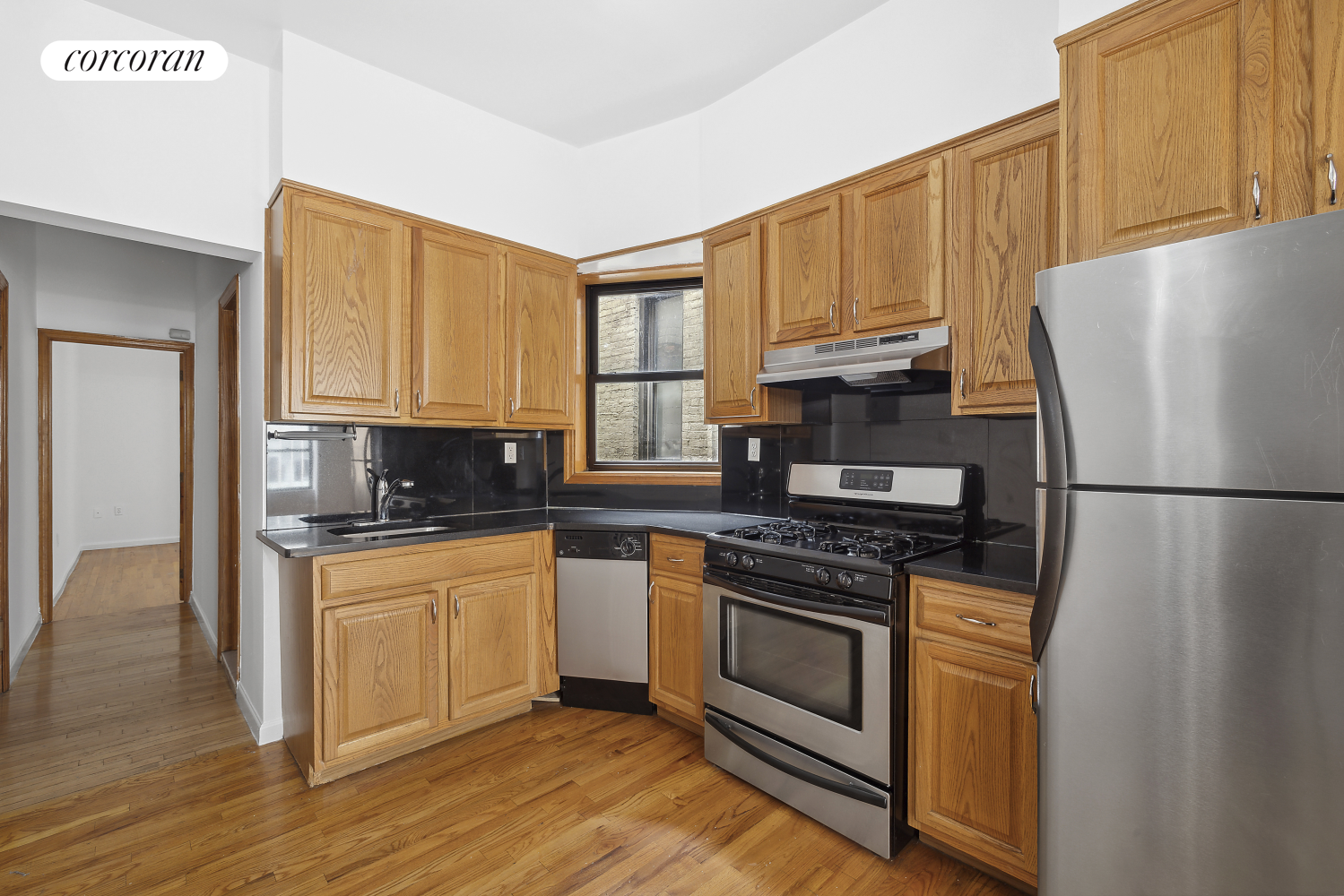 a kitchen with granite countertop wooden floors stainless steel appliances and white cabinets