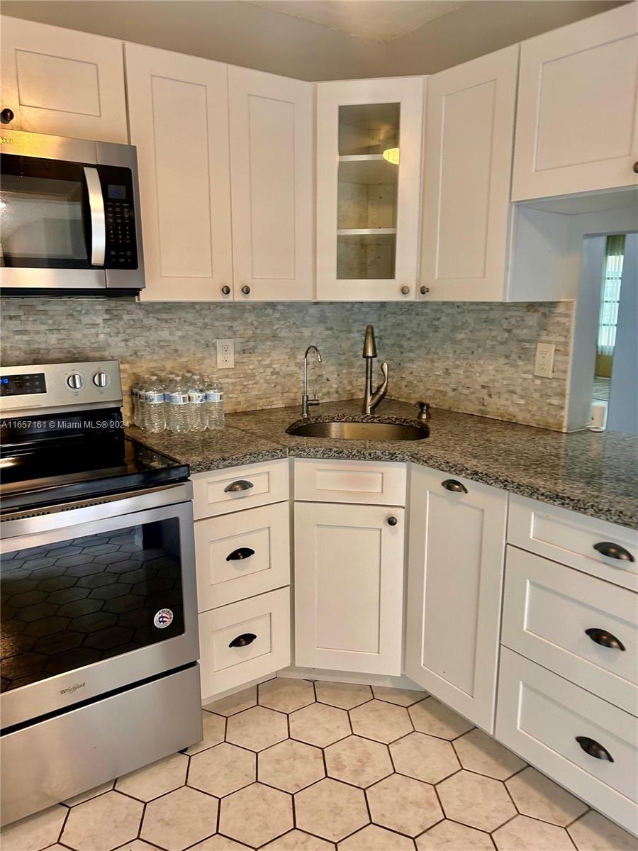 a kitchen with granite countertop white cabinets stainless steel appliances and a sink