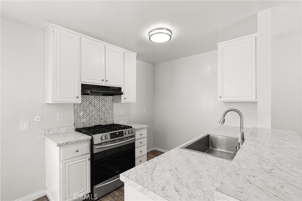 a kitchen with granite countertop a stove and a white cabinets