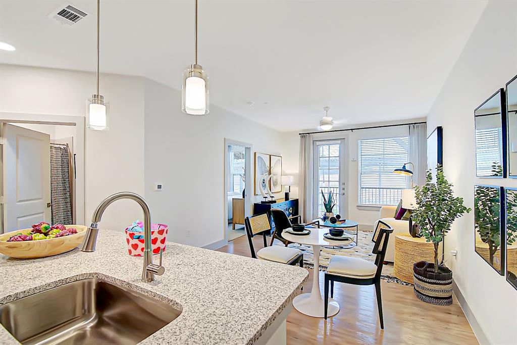 a kitchen with a sink dishwasher a dining table and chairs with wooden floor