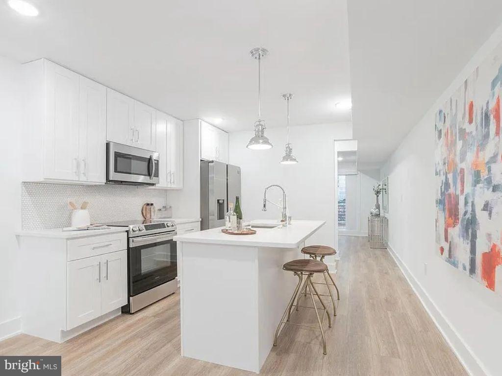 a kitchen with a sink a counter top space stainless steel appliances and cabinets