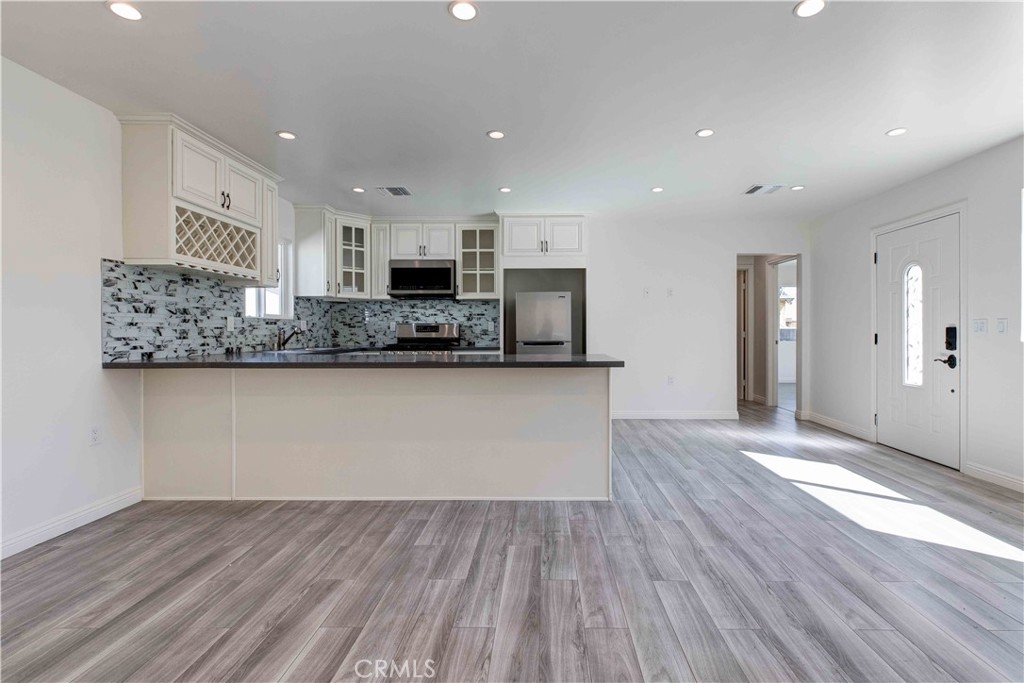 a view of kitchen with stainless steel appliances granite countertop cabinets and wooden floor