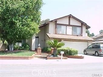 a view of a house with a yard plants and a car parked in front of it