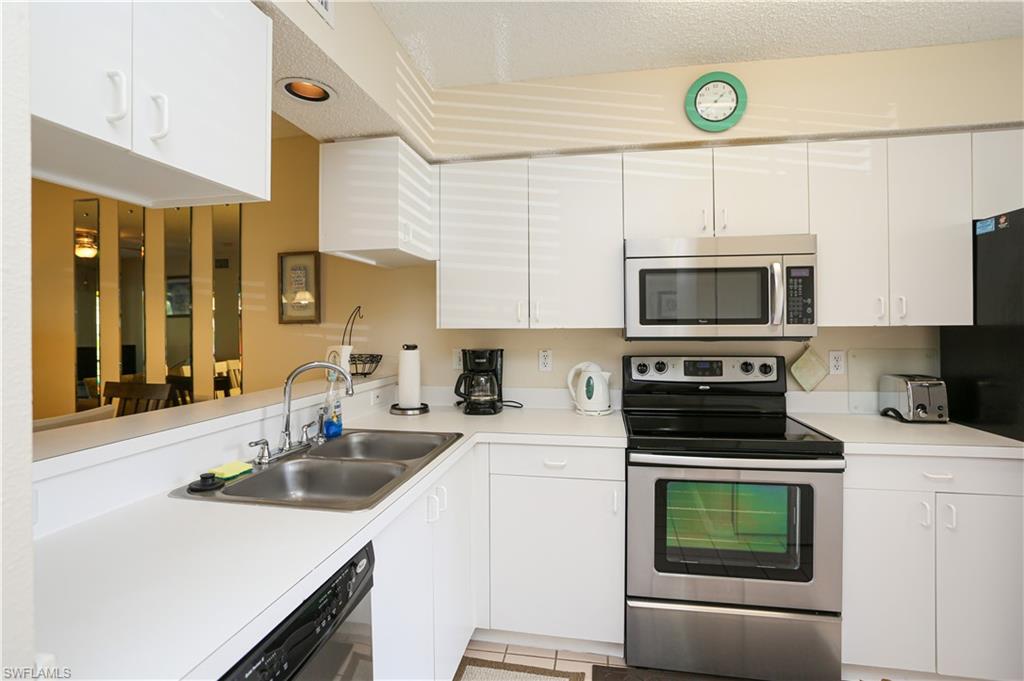 Kitchen with stainless steel appliances, sink, a textured ceiling, white cabinets, and light tile patterned floors