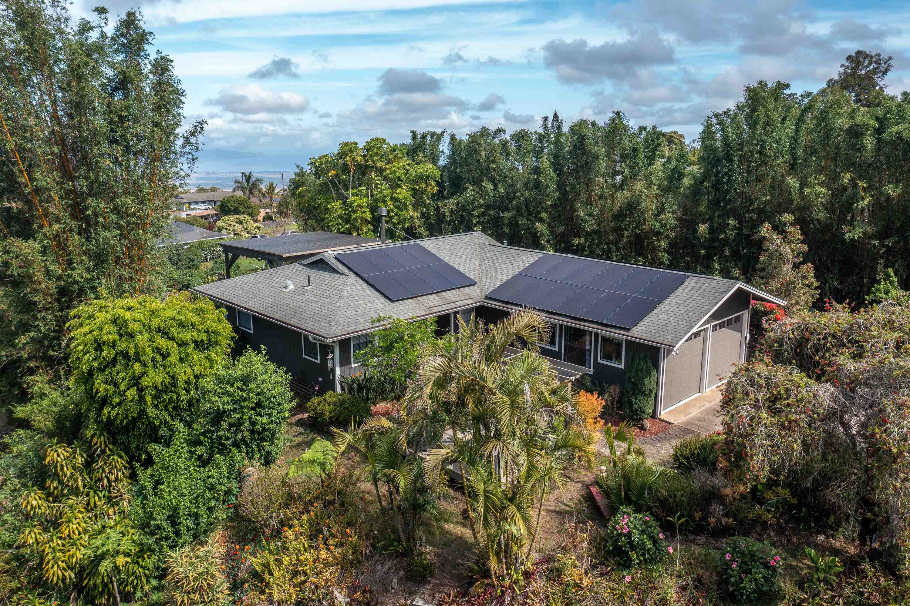 an aerial view of a house with yard and trees in the background