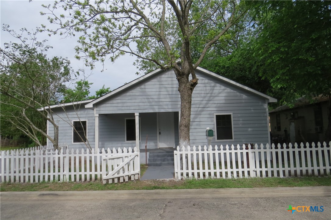 a house that has a tree in front of it with wooden fence