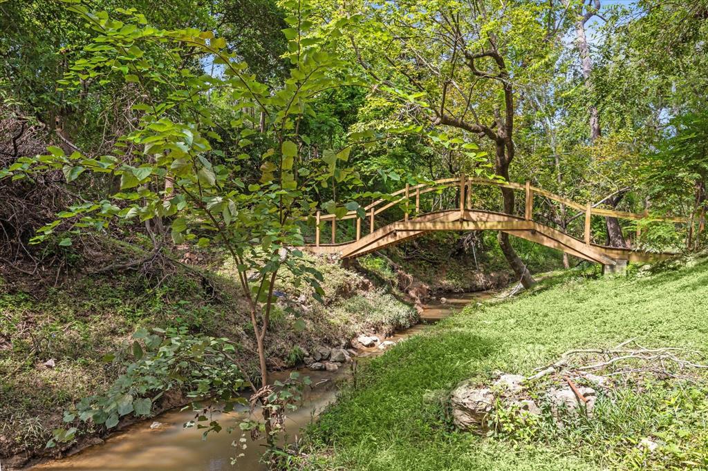 Enjoy your own wooden footbridge crossing over a gentle stream, surrounded by lush greenery and mature trees.