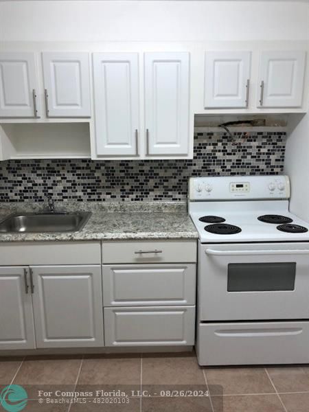 a kitchen with granite countertop white cabinets and stainless steel appliances